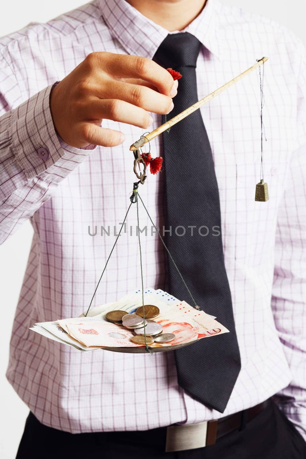 Mid section view of a businessman weighing paper currency with coins on a weighing scale