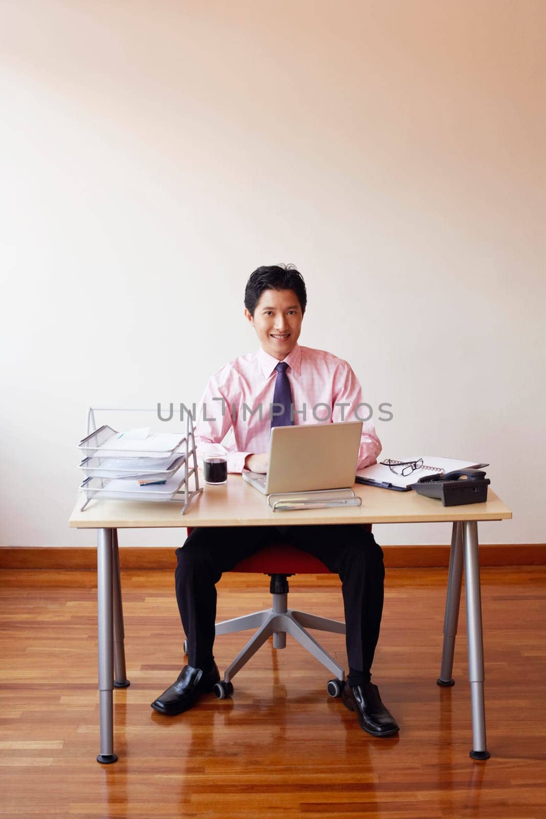 Portrait of a businessman sitting in an office with a laptop and smiling