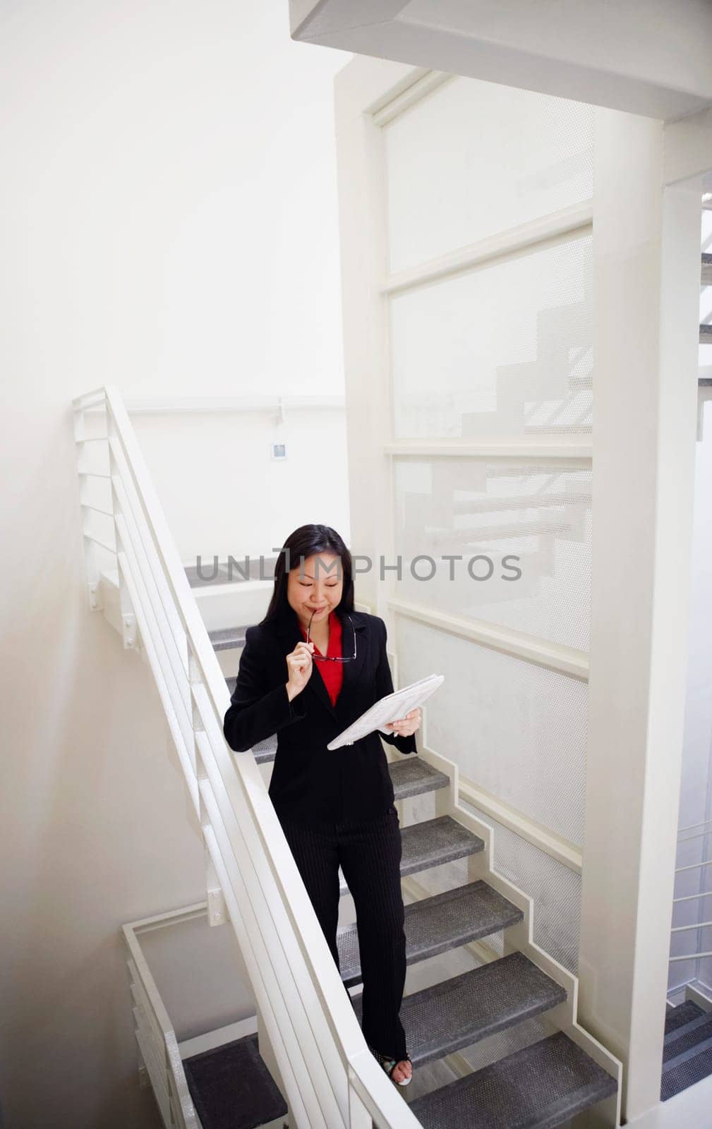 High angle view of a businesswoman holding a newspaper and walking down a staircase
