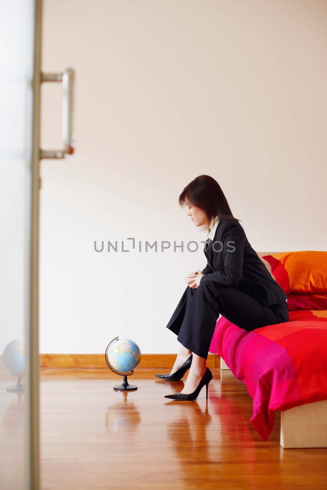 Side profile of a businesswoman sitting on the bed and looking at a globe