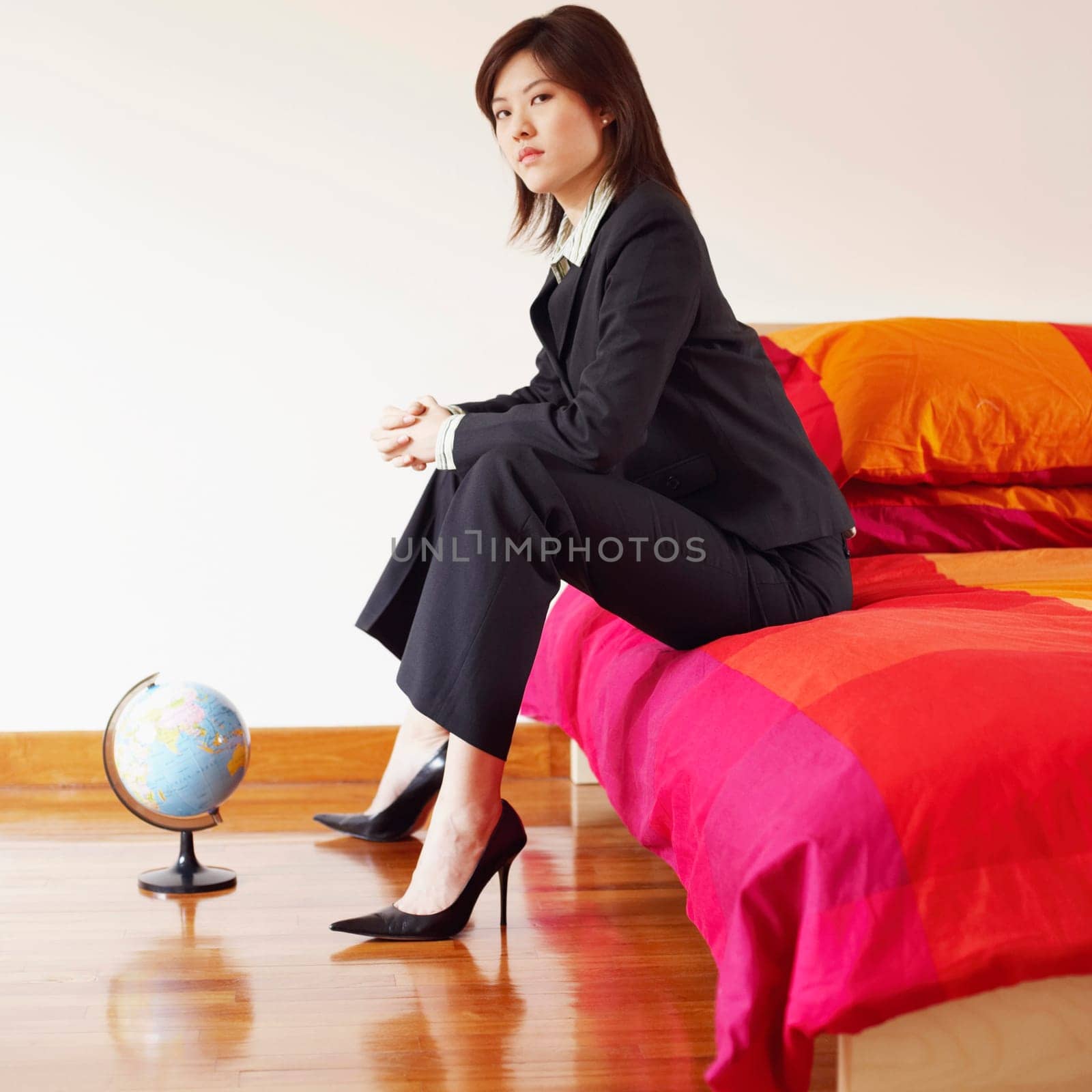 Portrait of a businesswoman sitting on the bed with her hands clasped