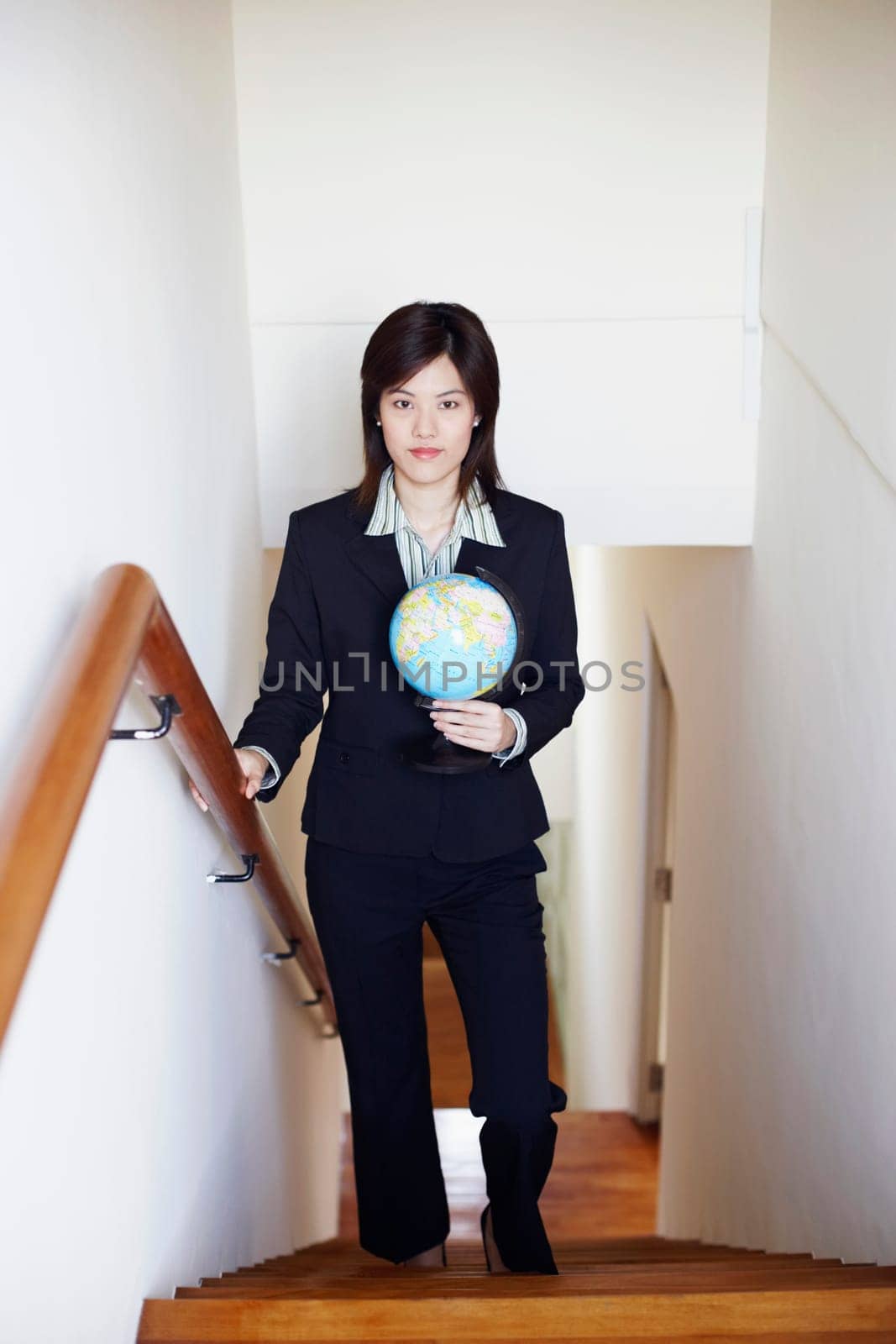 Portrait of a businesswoman holding a globe and walking on the staircase