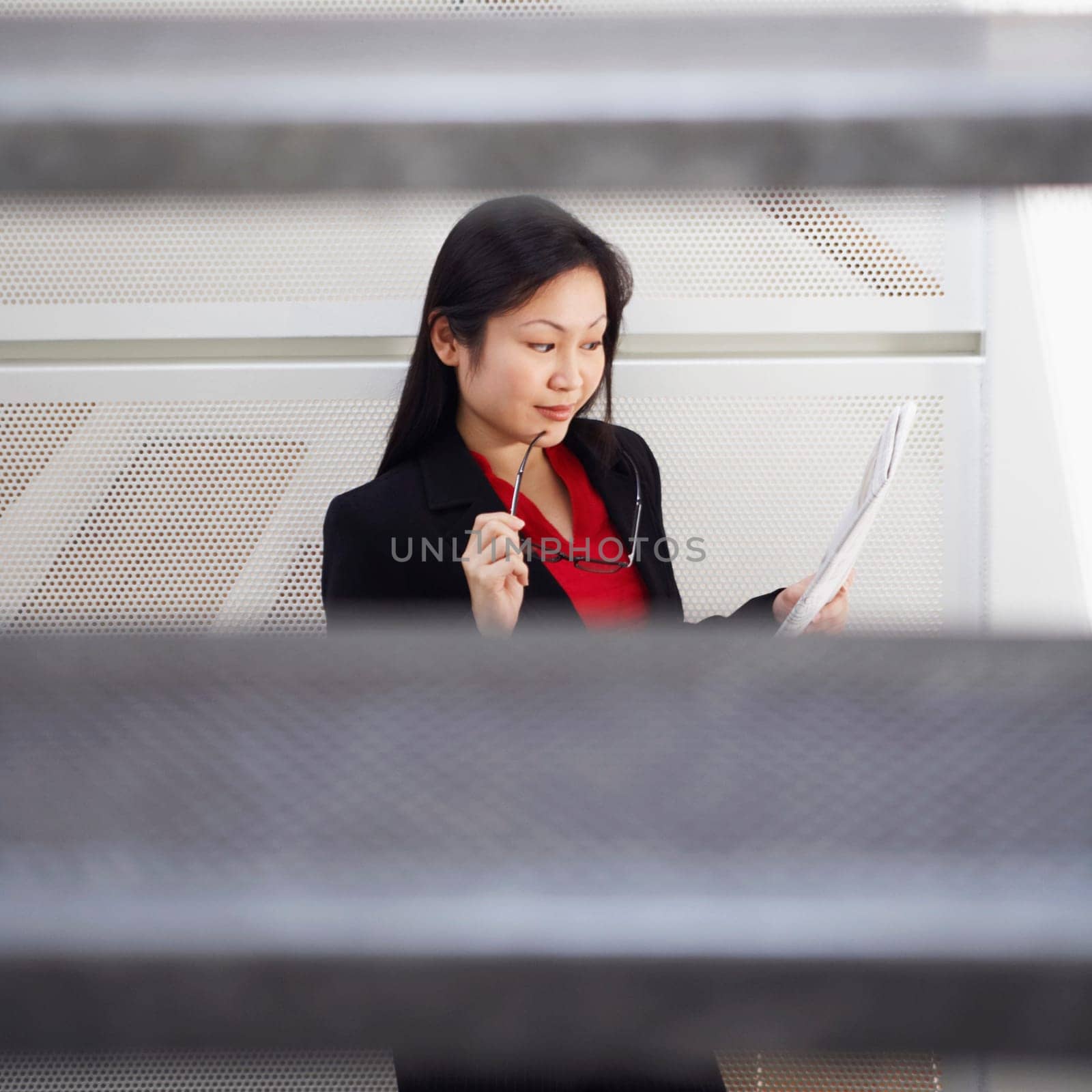 High angle view of a businesswoman holding eyeglasses and reading a newspaper