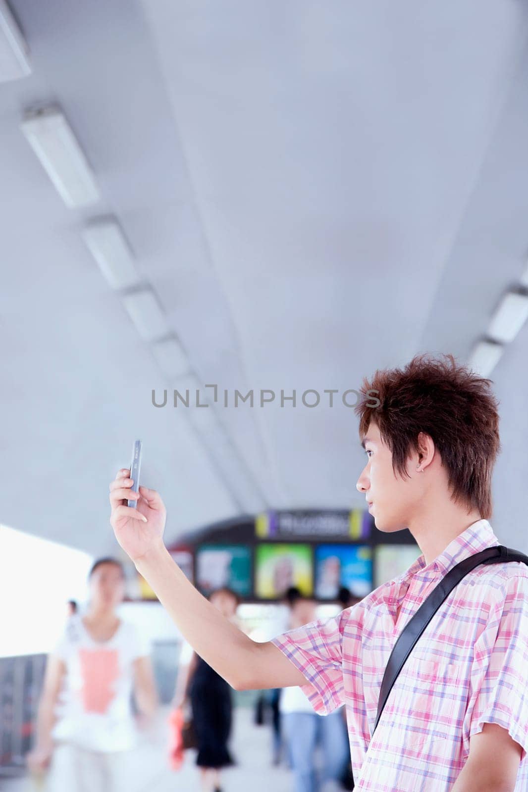 Side profile of a young man taking a picture with his mobile phone