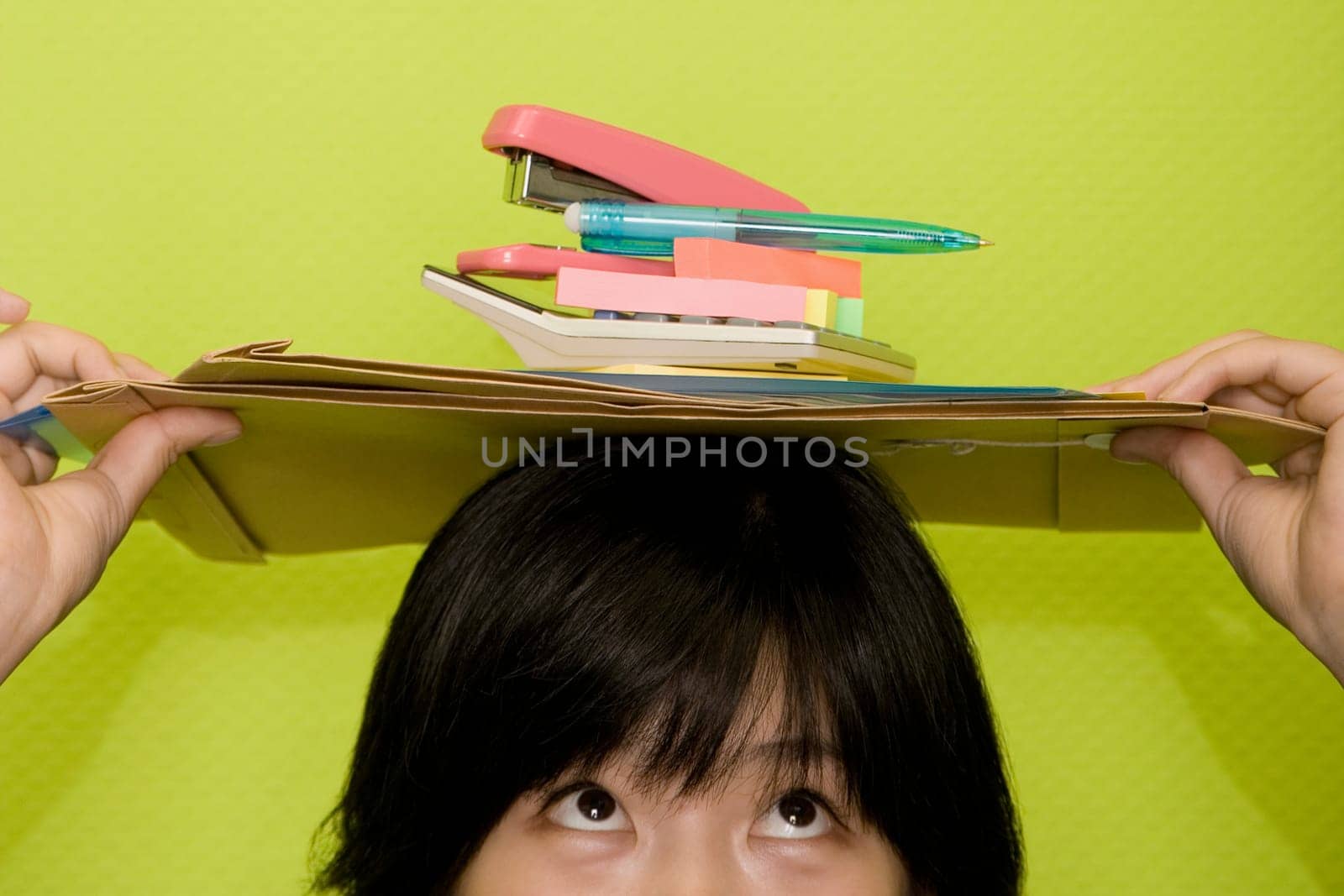 Young woman holding office stationeries on her head