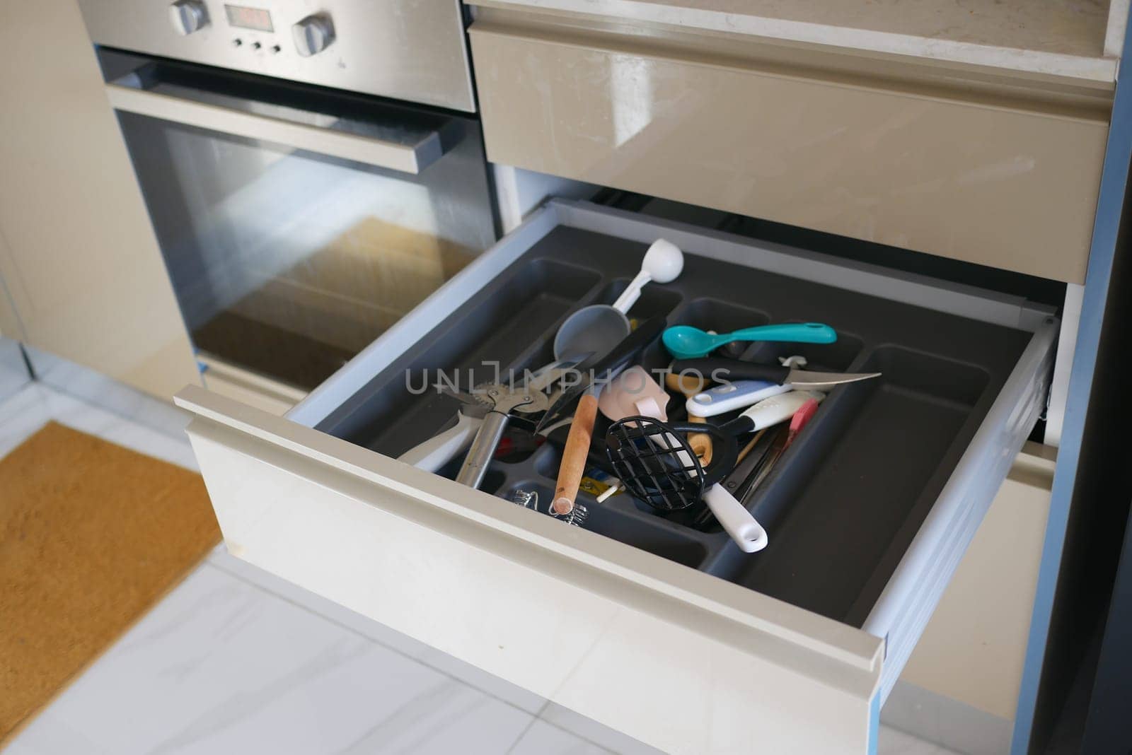 Assorted kitchen utensils are seen cluttered in a drawer in a modern kitchen.