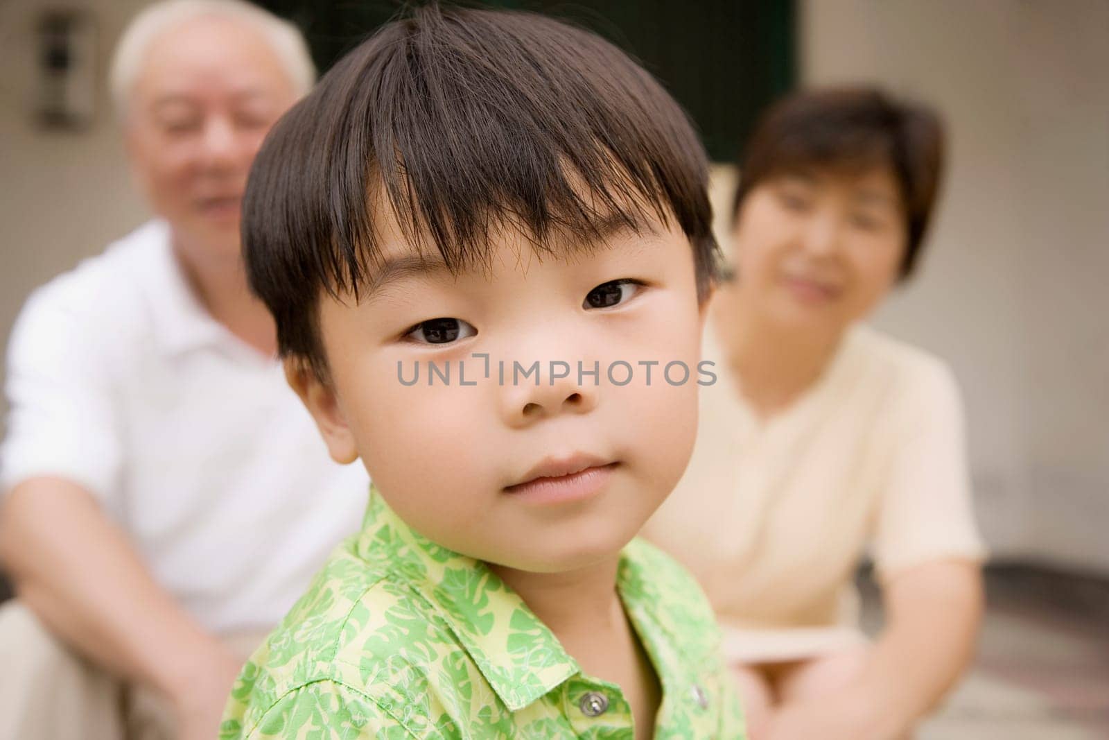 Portrait of a boy with his grandparents sitting behind him