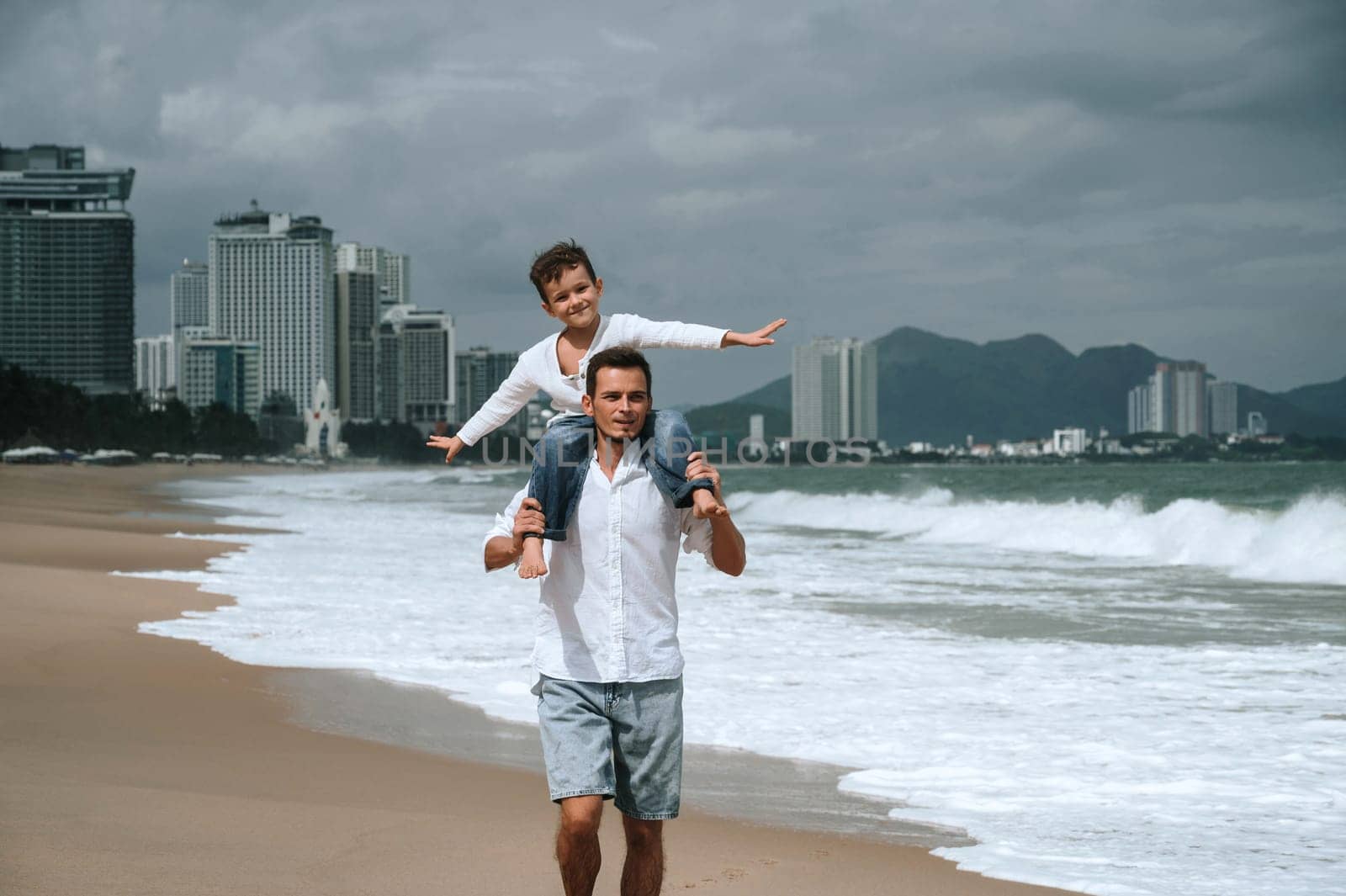 happy father dad with a child son on are walking along the beach by the sea on a summer vacation