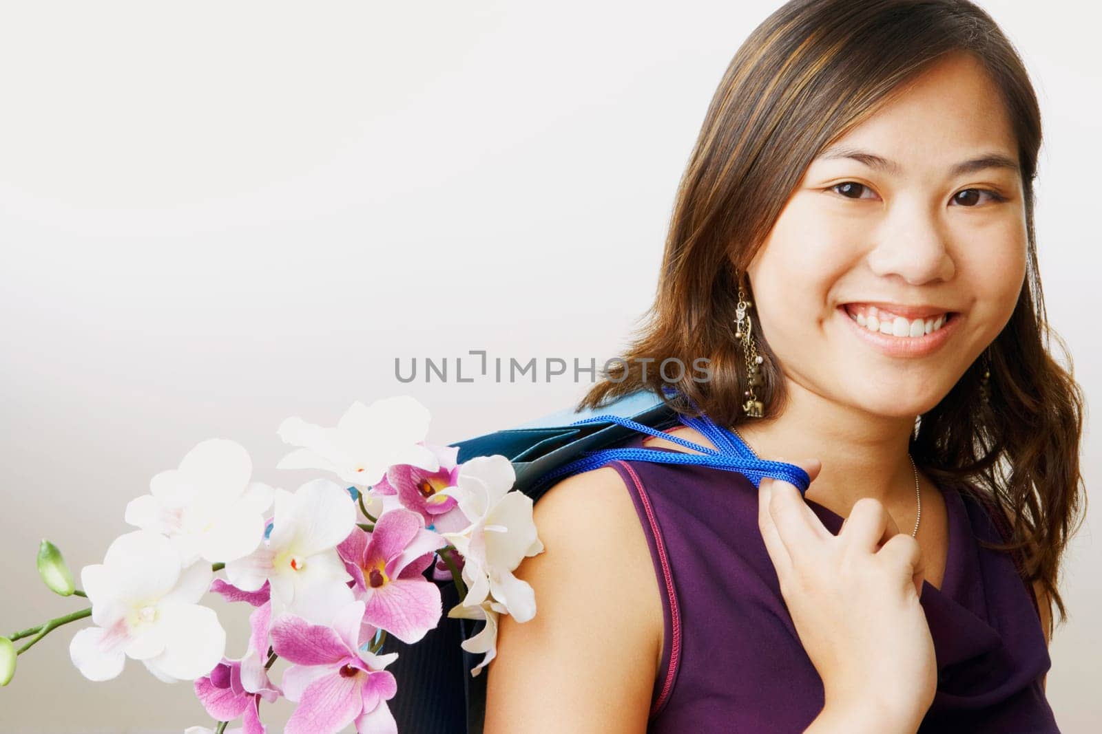 Portrait of a young woman carrying flowers in a shopping bag