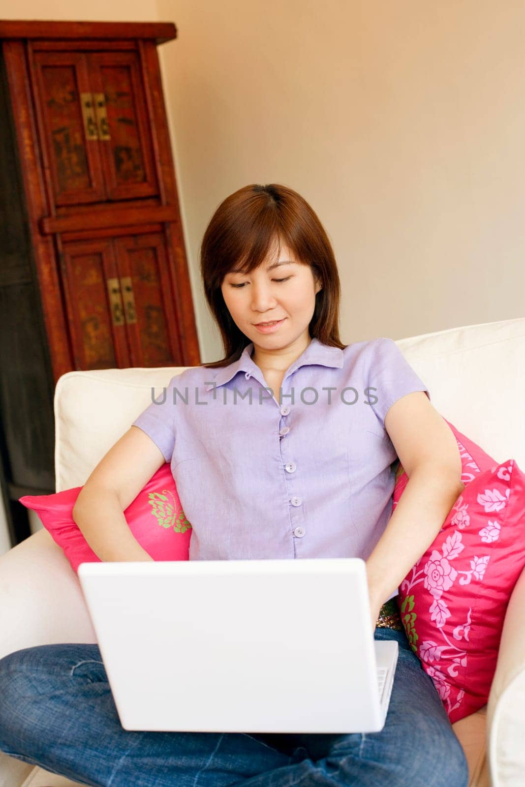 Young woman sitting in an armchair and working on a laptop