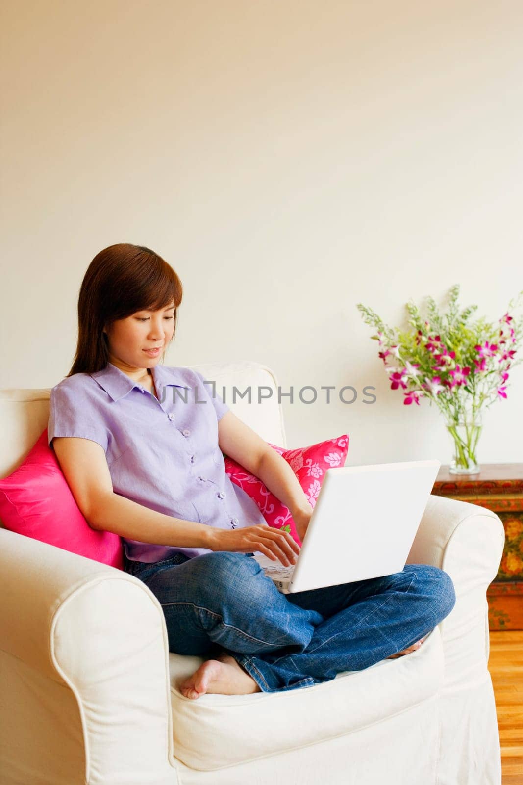 Young woman sitting in an armchair and working on a laptop
