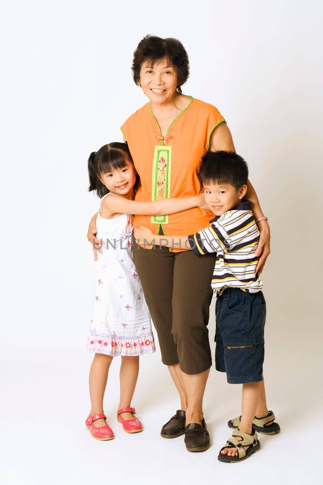 Portrait of a mature woman standing with her grandson and a granddaughter