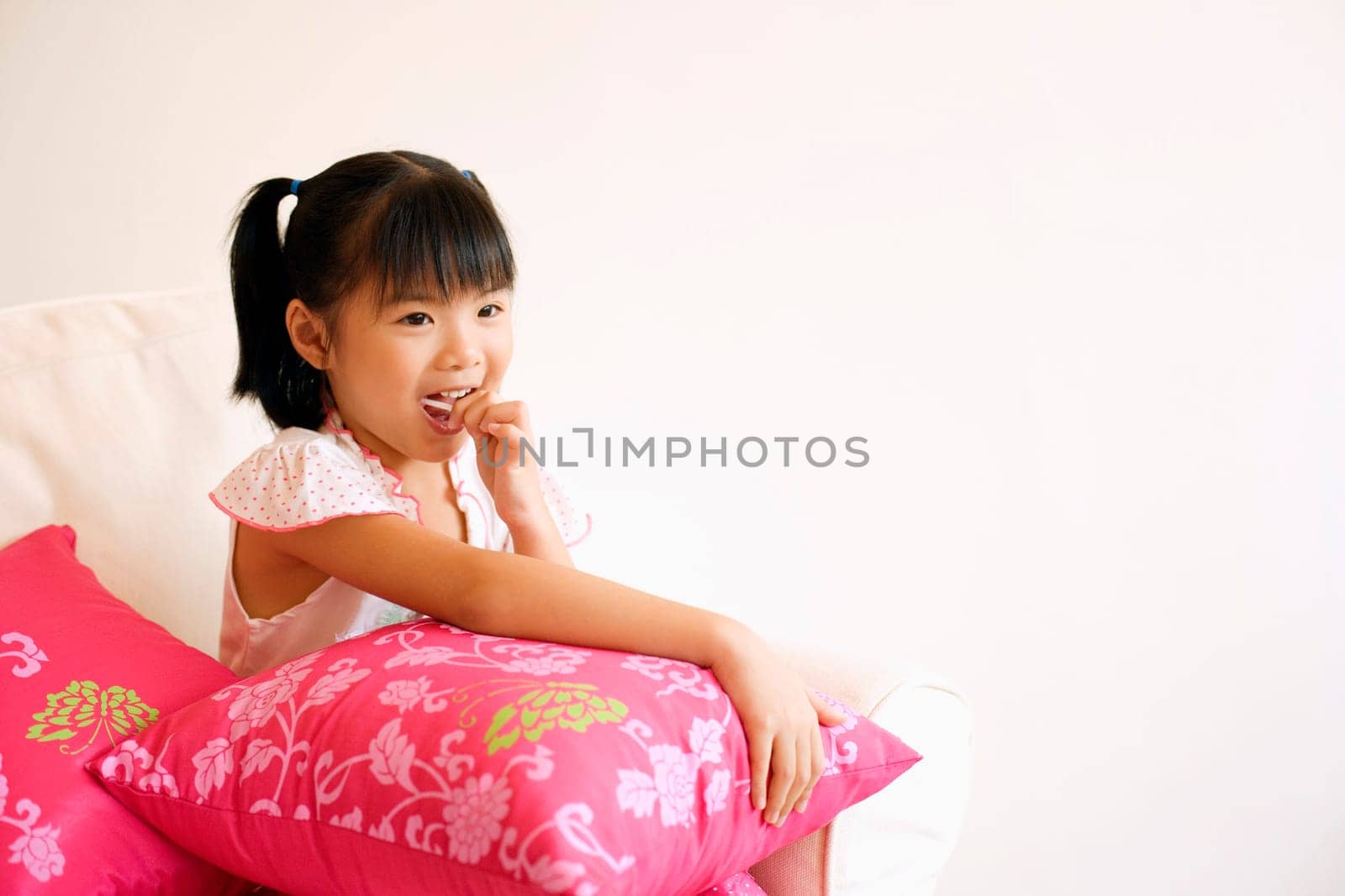 Close-up of a girl sitting on a couch and eating a lollipop