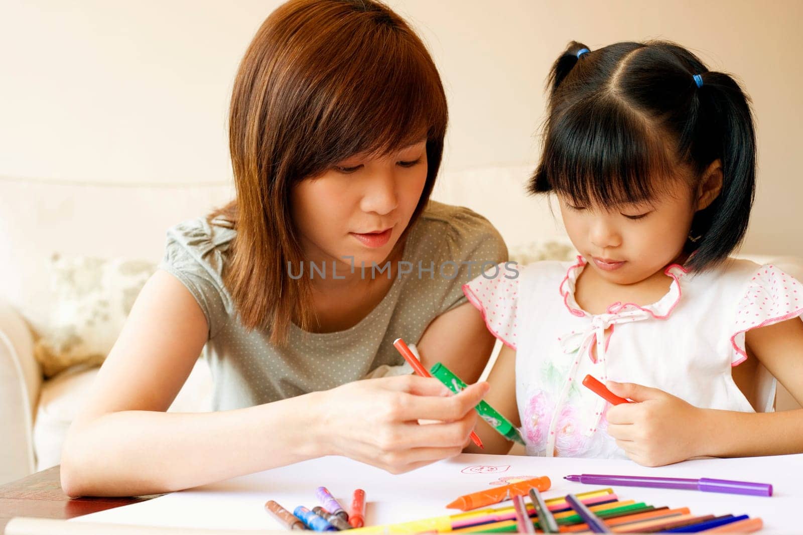Close-up of a young woman teaching her daughter to color