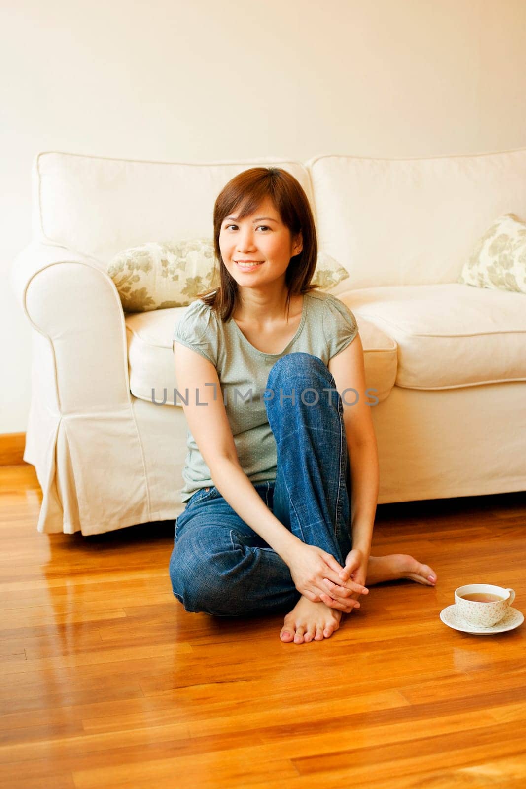 Portrait of a young woman sitting on the floor with a cup of tea beside her