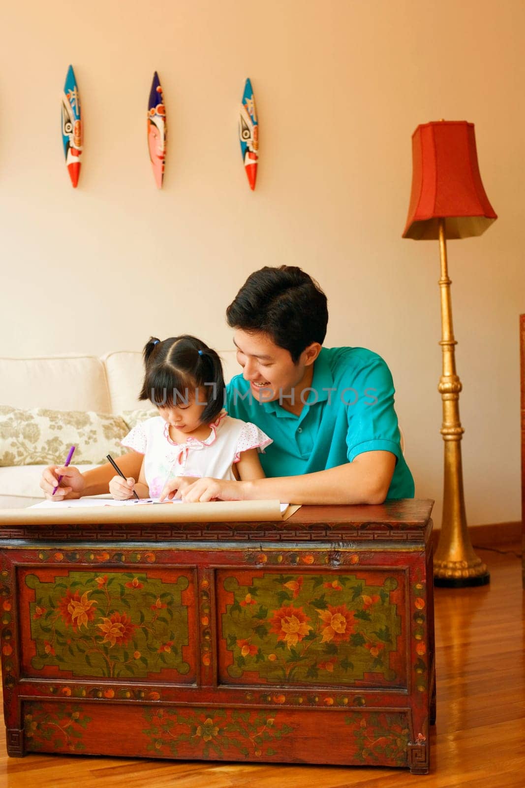 Young man teaching his daughter to color