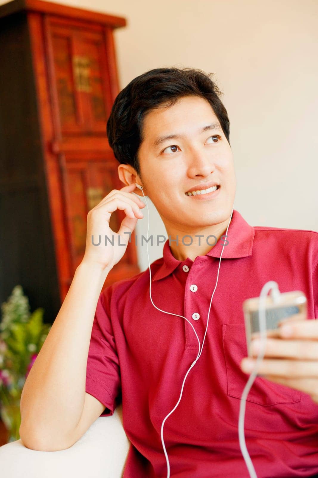 Close-up of a young man listening to an MP3 player and smiling