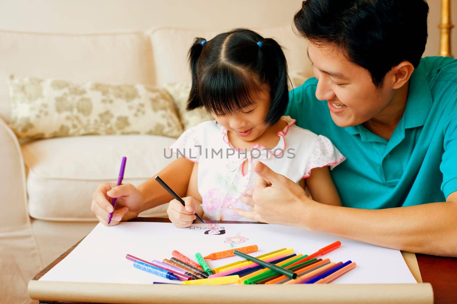 Young man teaching his daughter to color