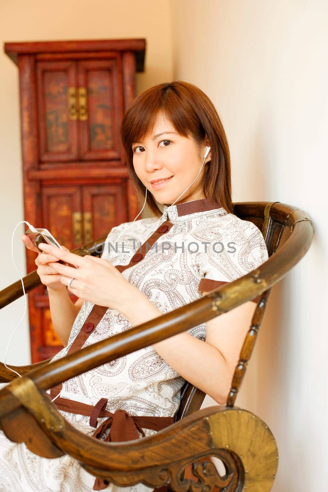 Portrait of a young woman sitting on a chair and listening to an MP3 player