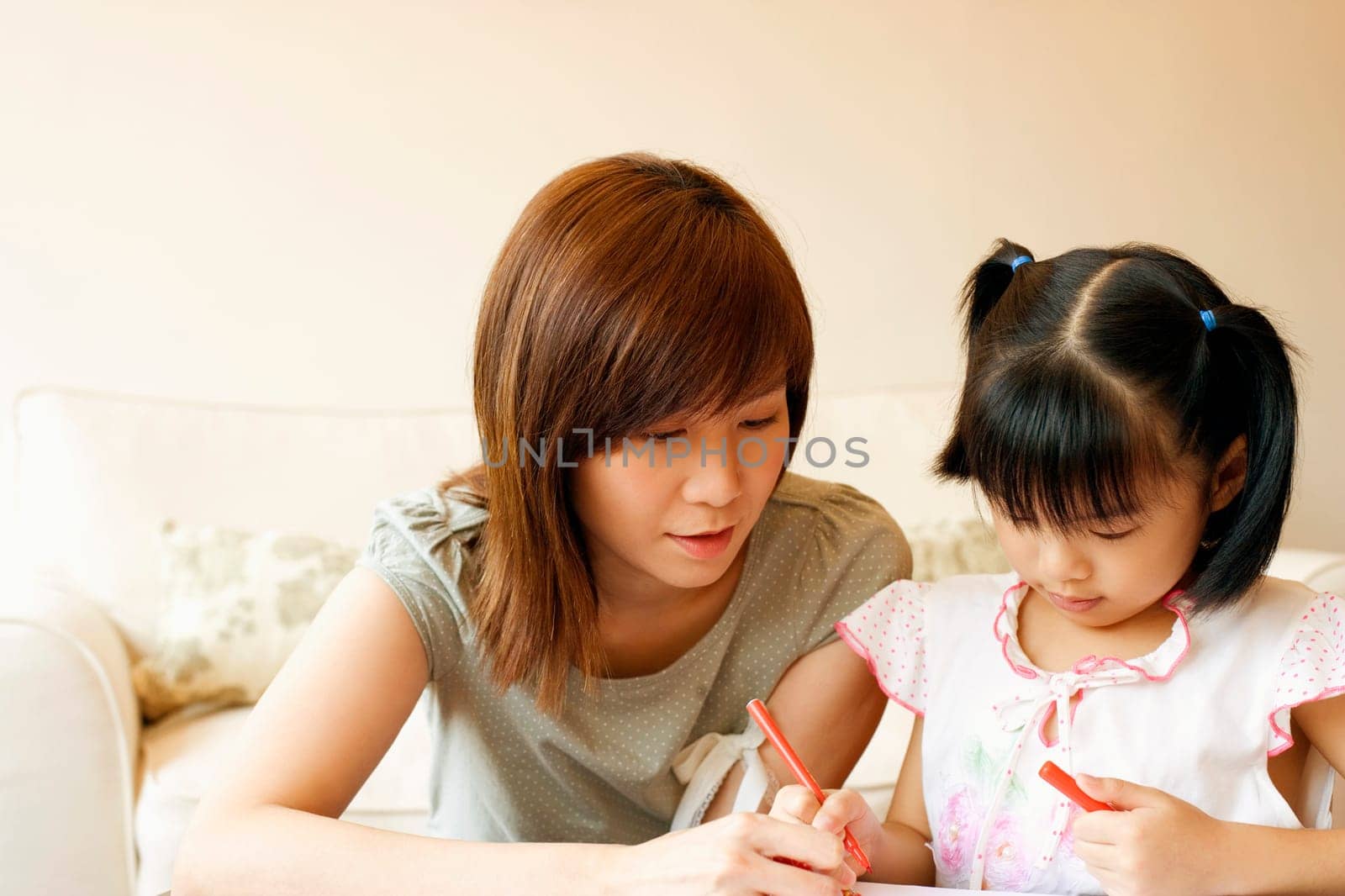 Close-up of a young woman teaching her daughter to color