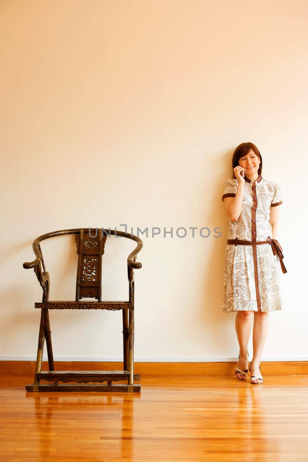 Young woman leaning against a wall and talking on a mobile phone