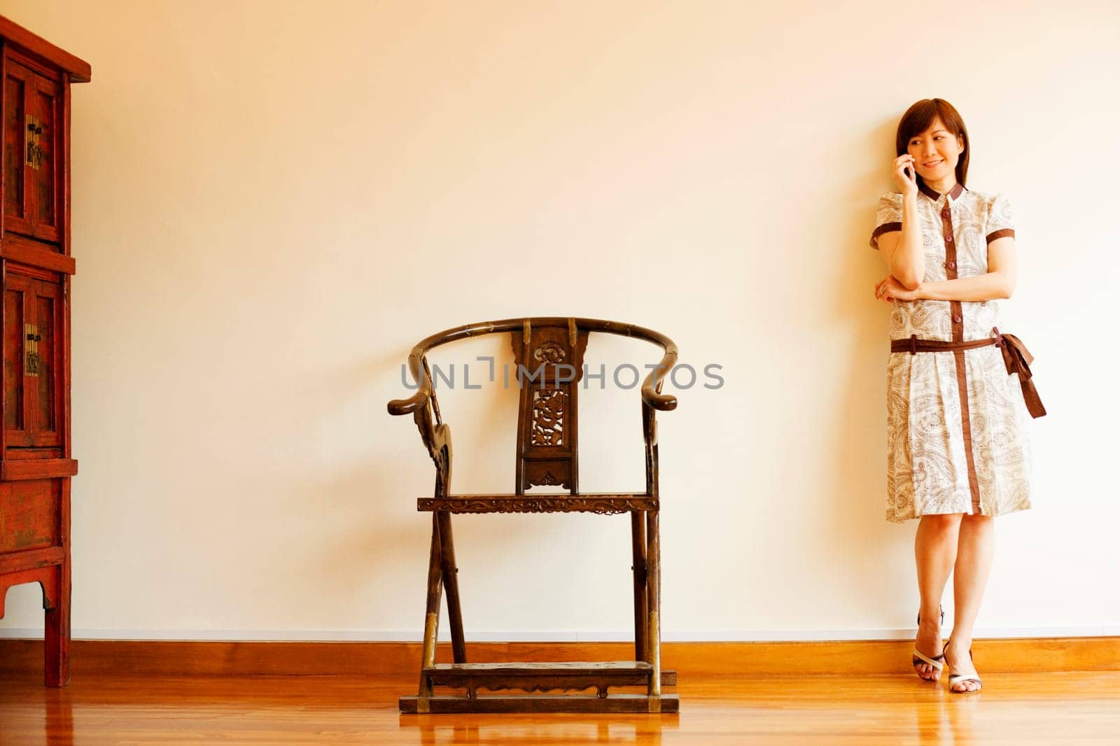 Young woman leaning against a wall and talking on a mobile phone