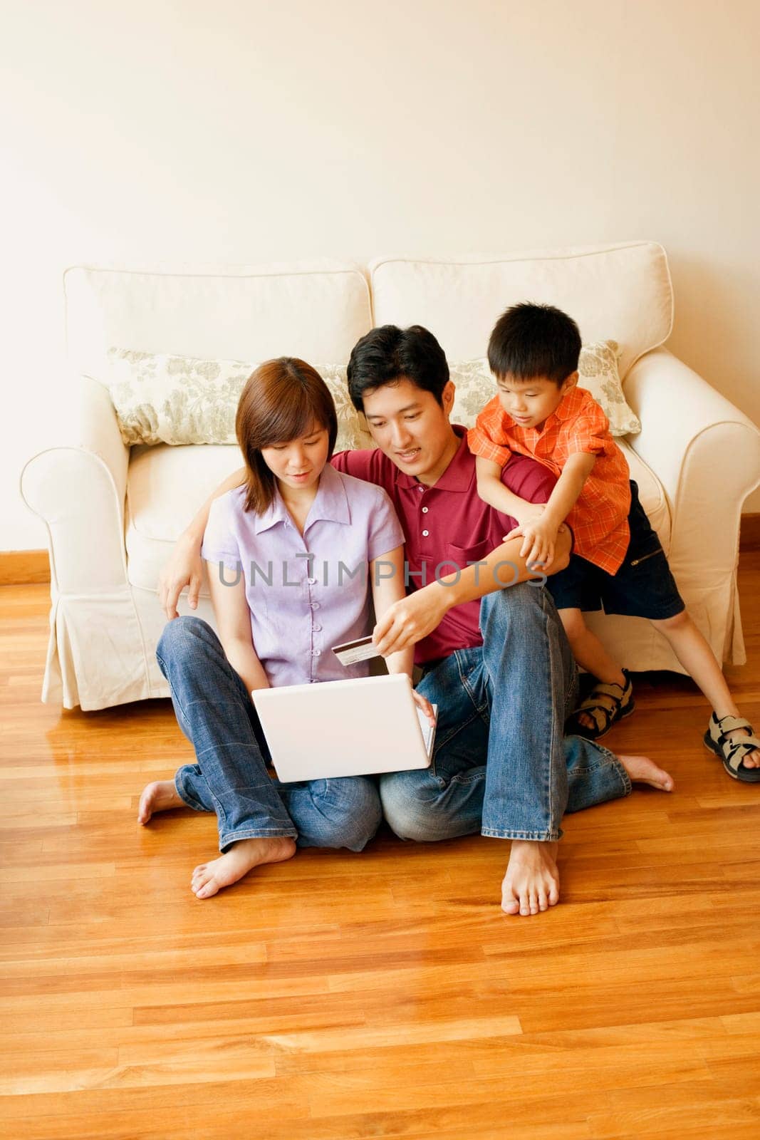 Young couple shopping online with a credit card and their son beside them