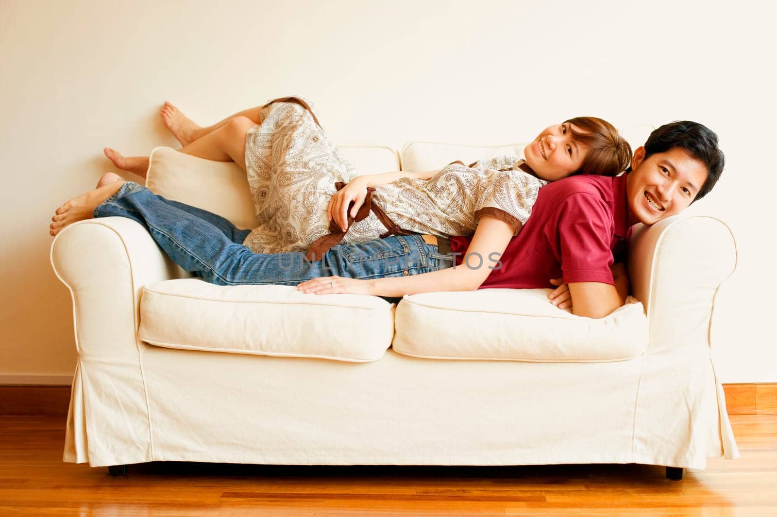 Portrait of a young couple lying back to back on a couch