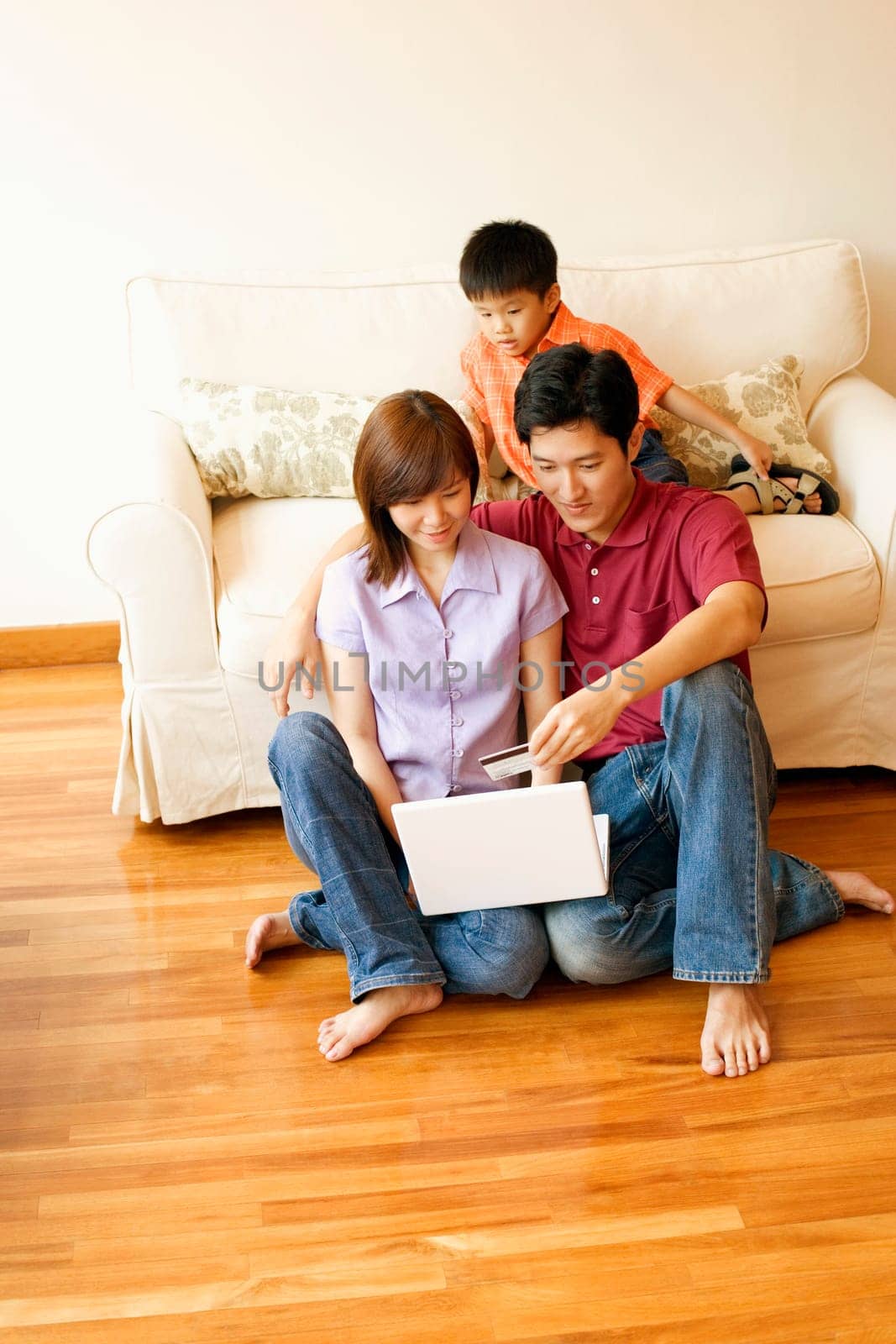 Young couple shopping online with a credit card and their son beside them