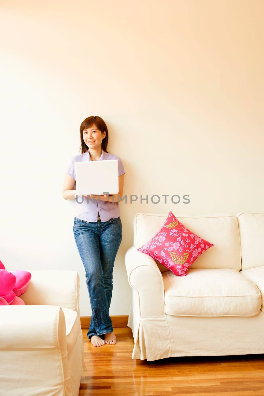 Young woman leaning against a wall and holding a laptop