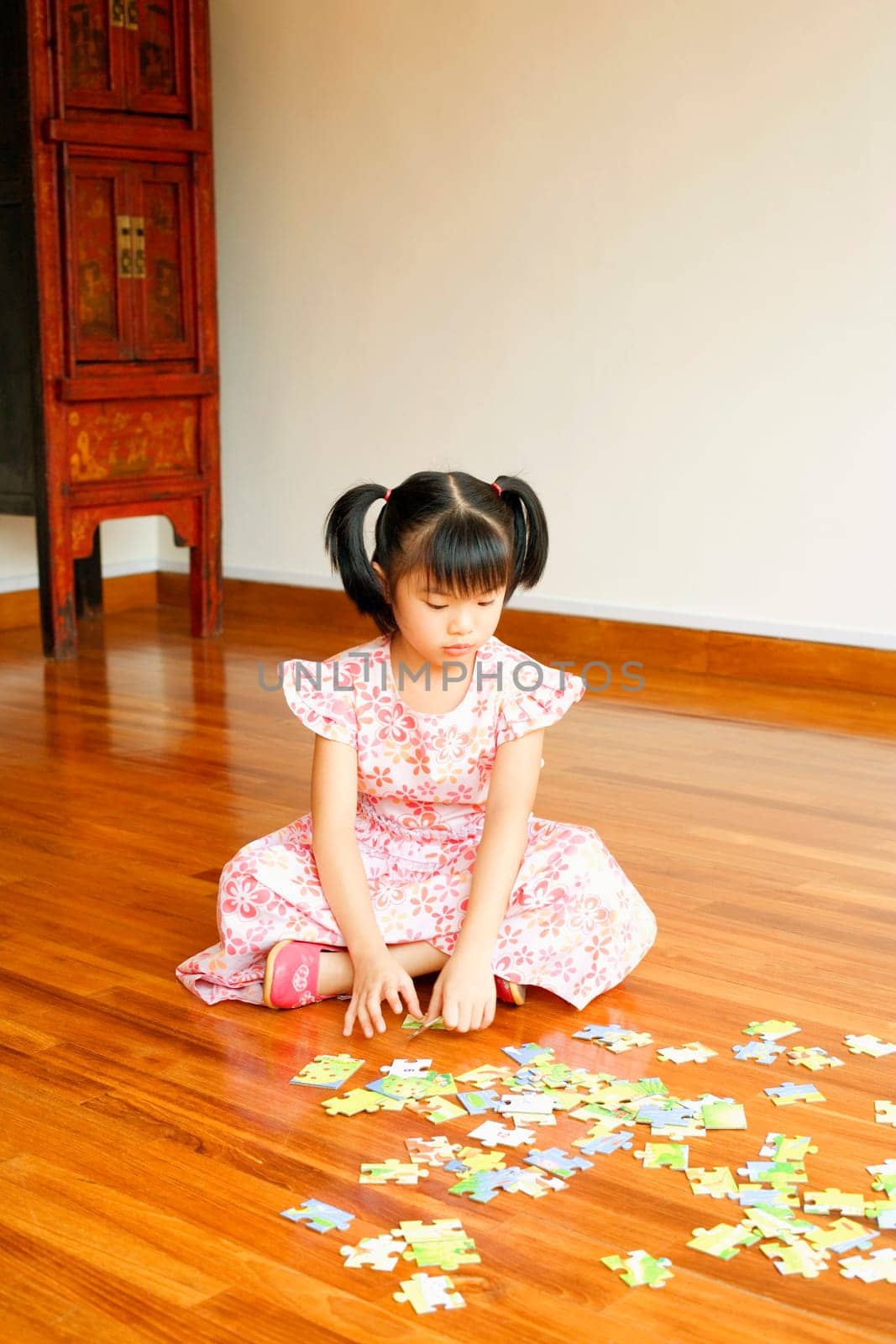 Close-up of a girl sitting on the floor and playing with a jigsaw puzzle