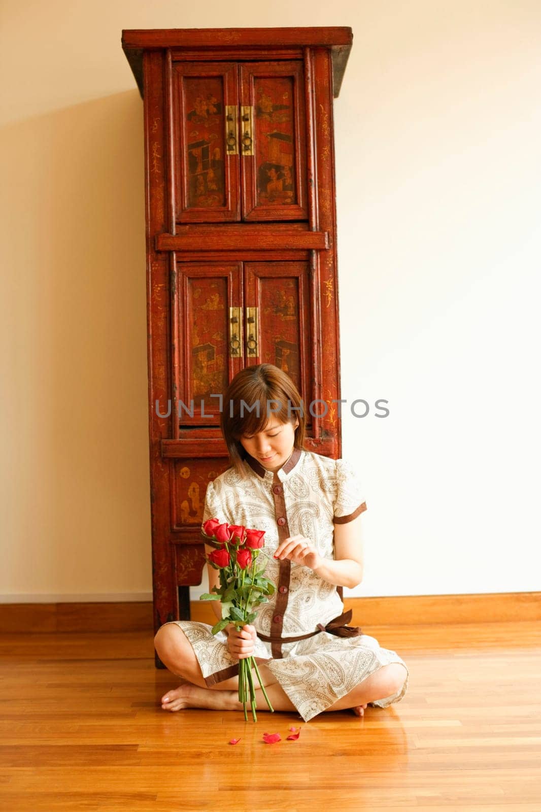 Close-up of a young woman sitting on the floor and plucking a rose