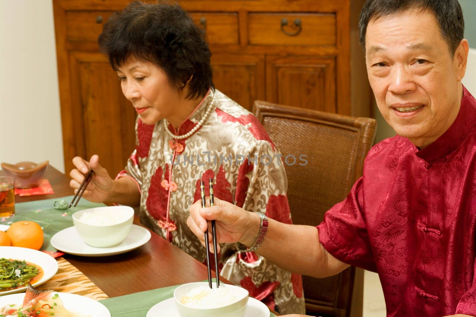 Portrait of a senior man sitting at a dining table with a mature woman beside him