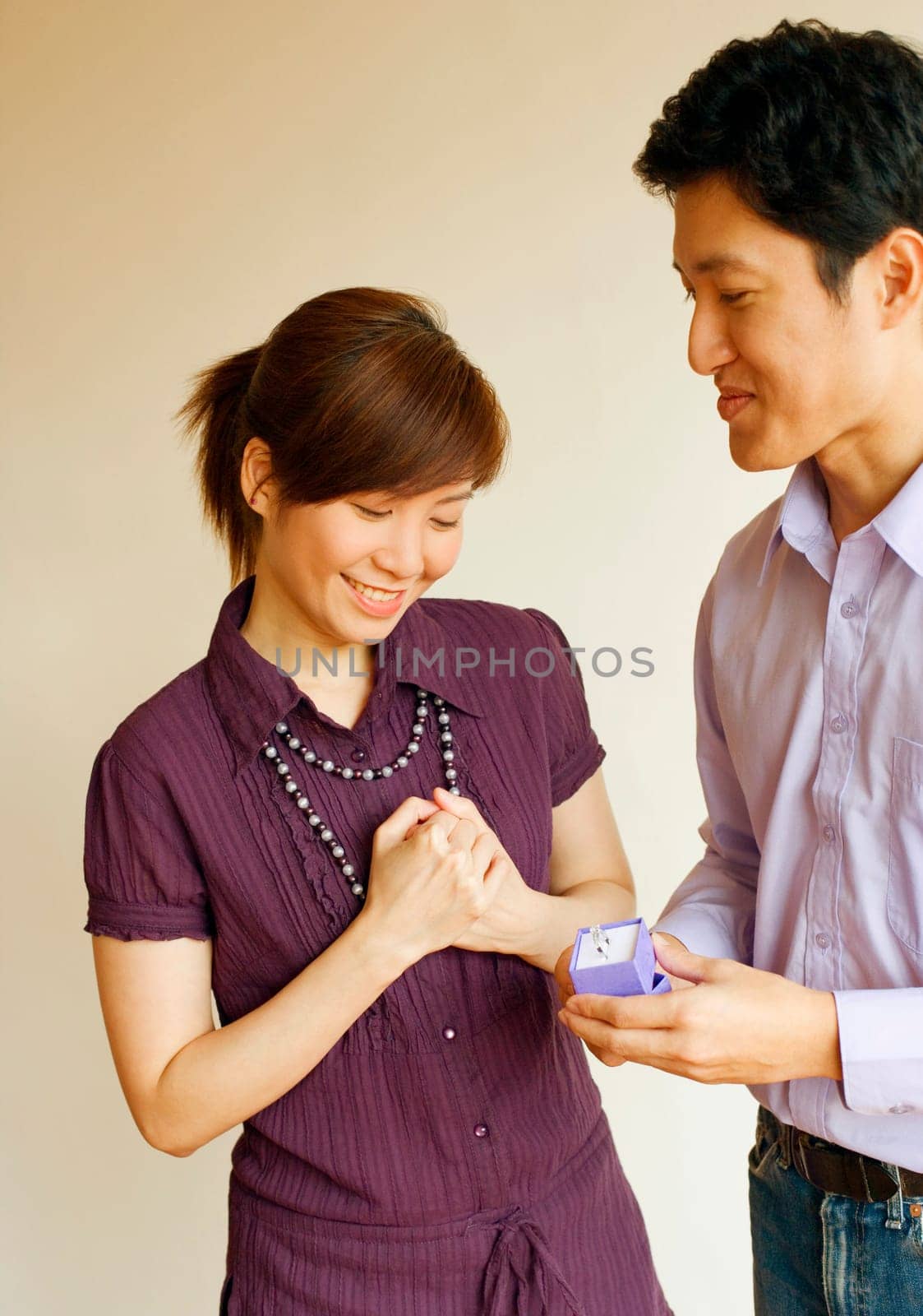 Close-up of a young man smiling and offering a ring to a young woman