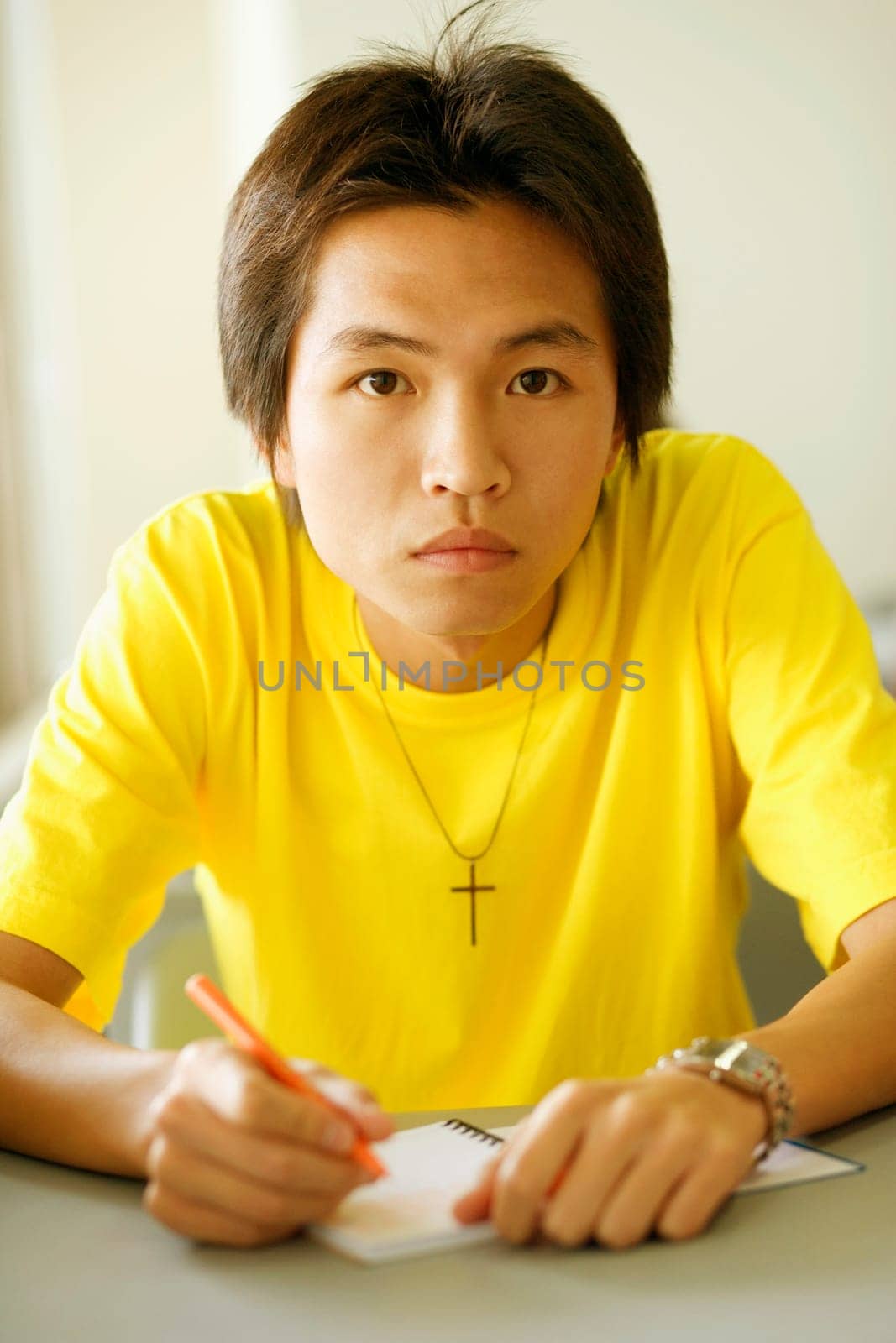 Portrait of a young man holding a pen on a notepad