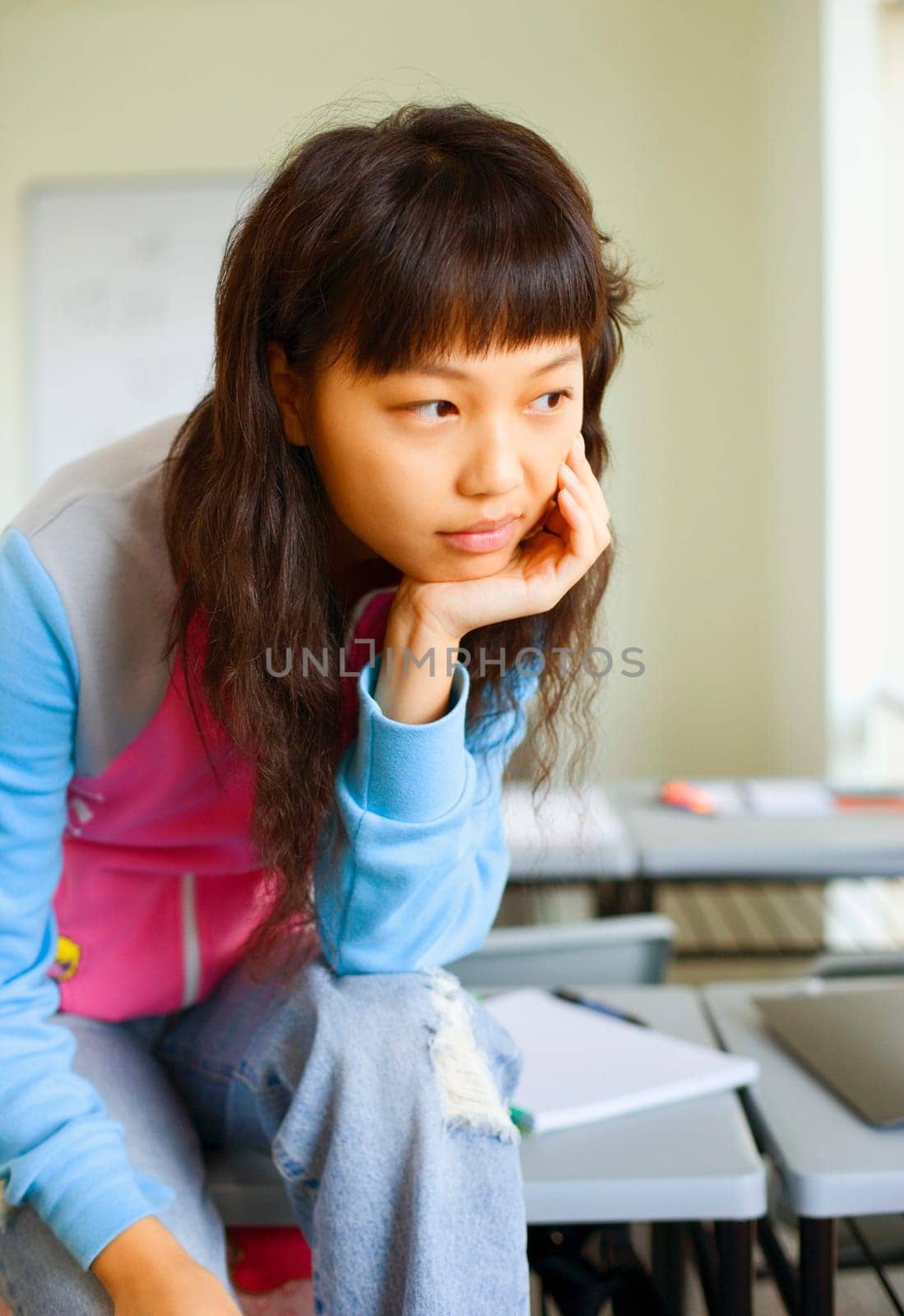 Close-up of a young woman sitting on desk and thinking in the classroom