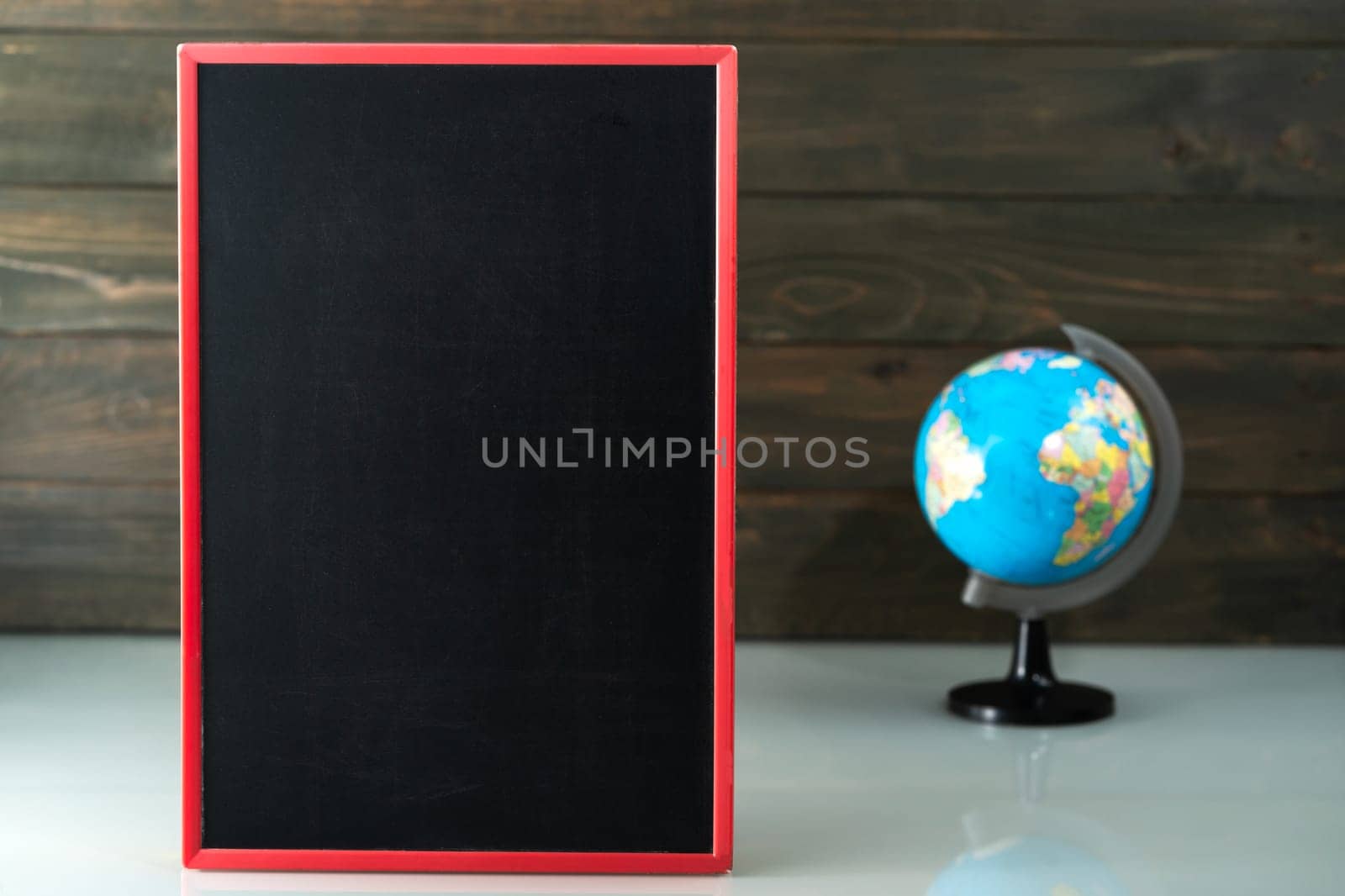 Chalkboard mock up frame and globe model on table near wood background in home