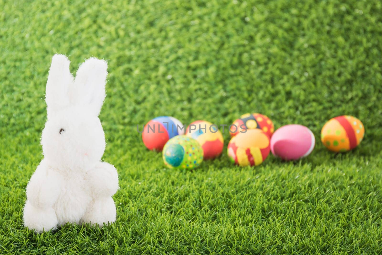 Easter bunny toy and Easter eggs on green grass