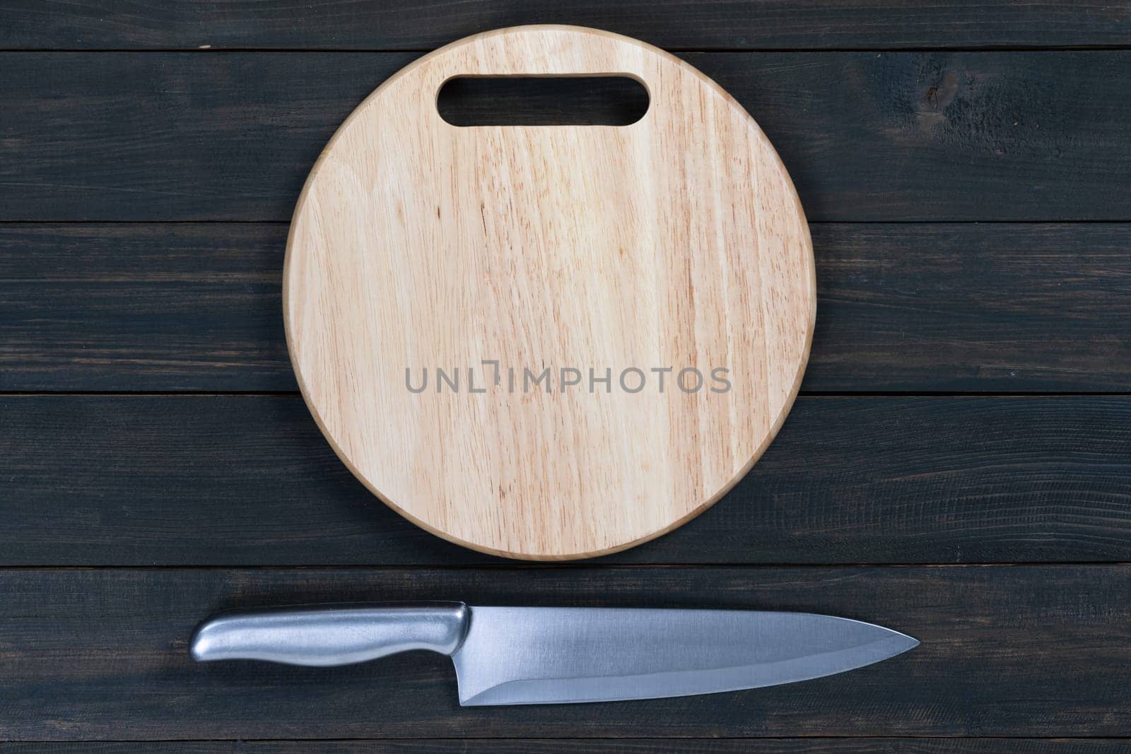 Close up kitchen knife and wooden round empty cutting board on a wooden table