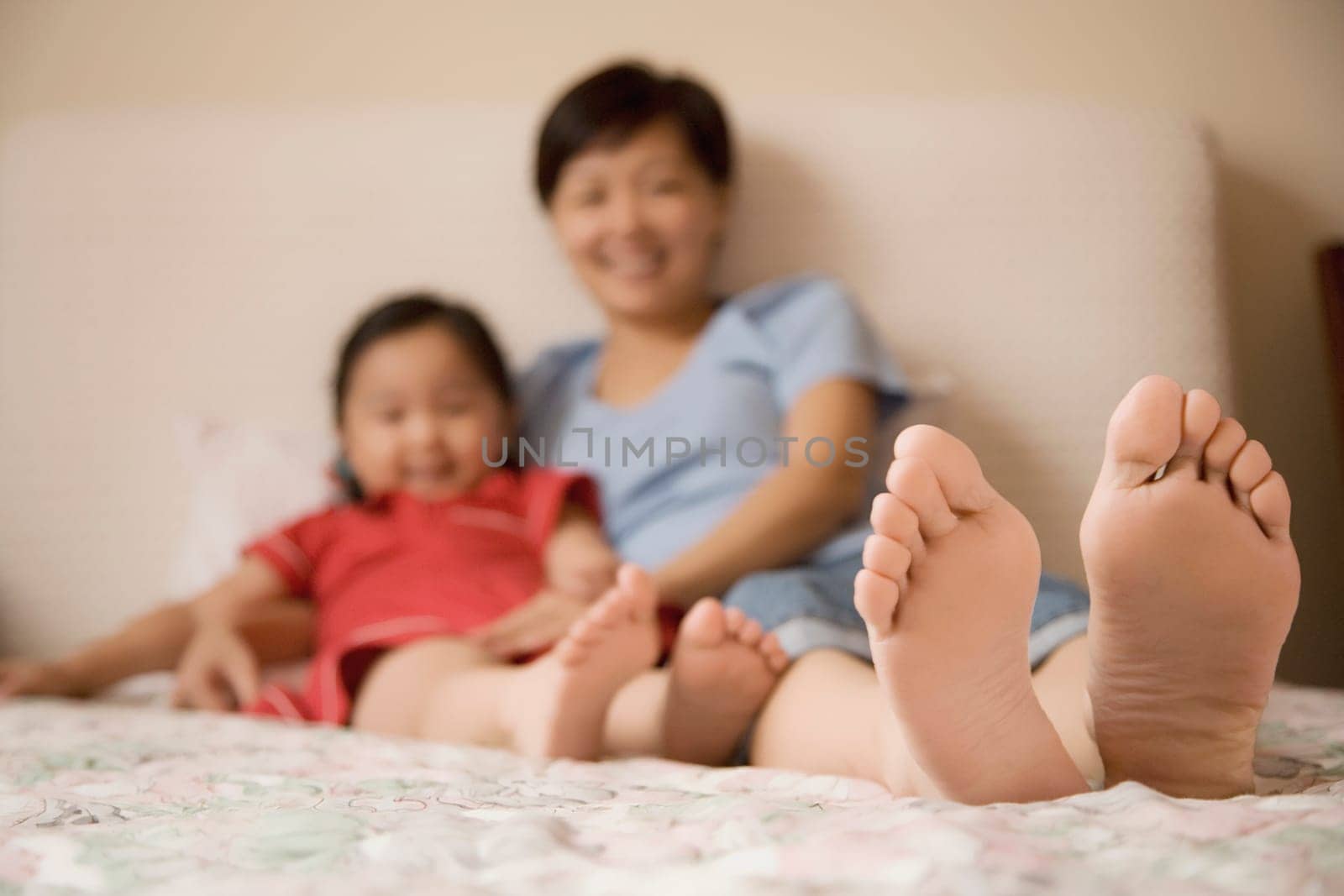 Mid adult woman and her daughter reclining on the bed