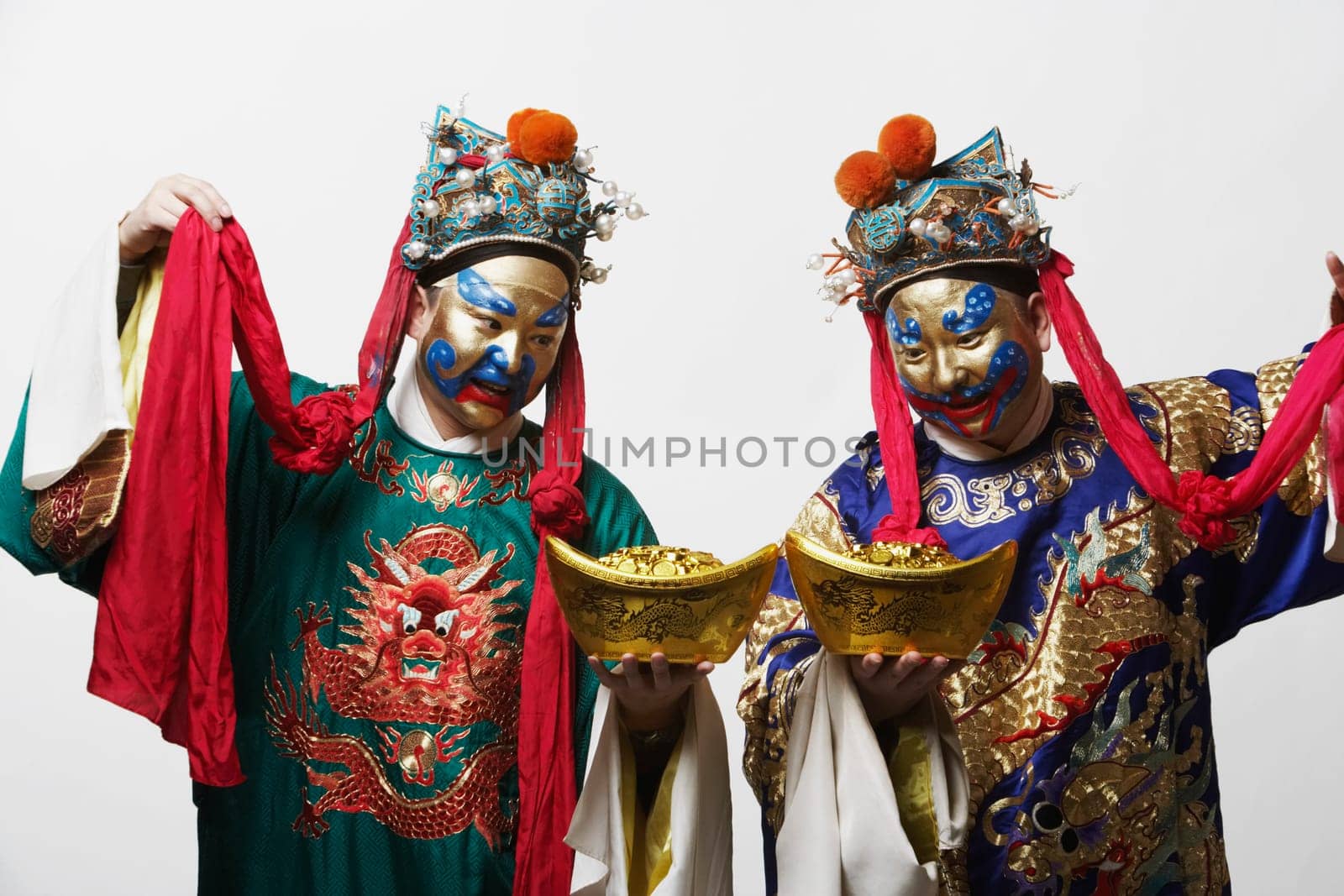 Close-up of two male Chinese opera performers holding bowls full of gold coins