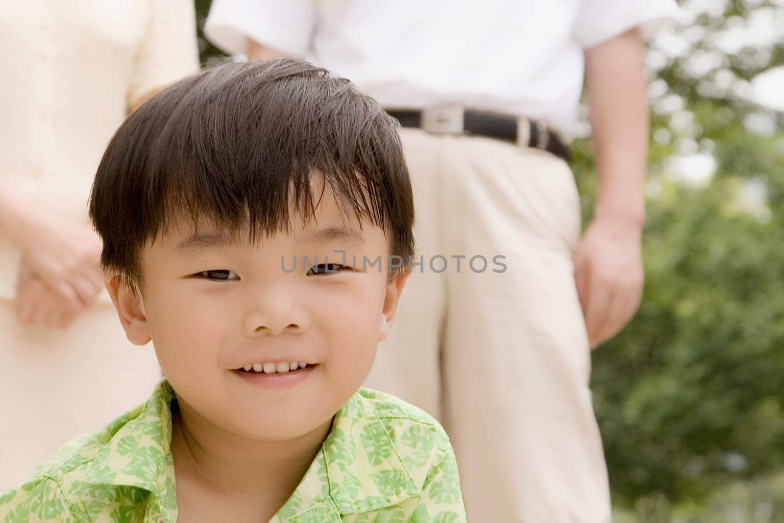 Portrait of a boy smiling with his grandparents standing behind him