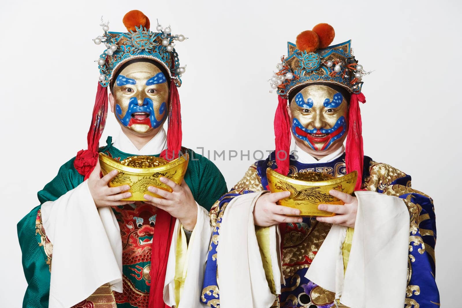 Portrait of two male Chinese opera performers holding bowls full of gold coins