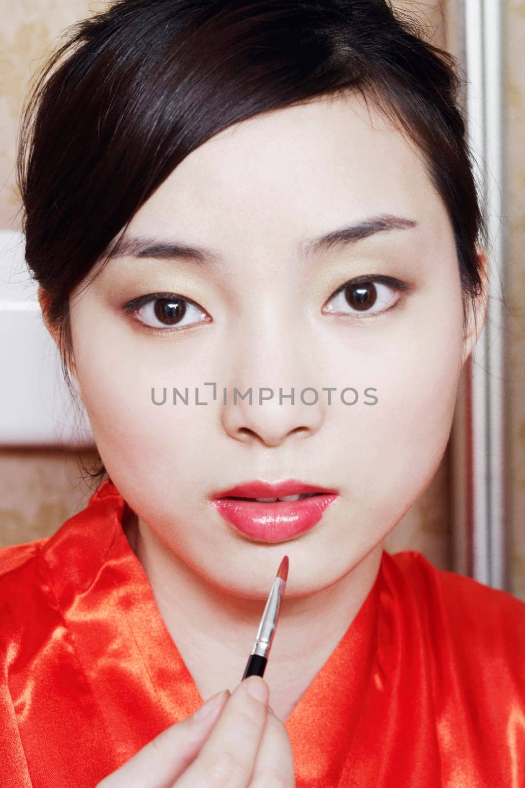 Portrait of a young woman applying lip gloss