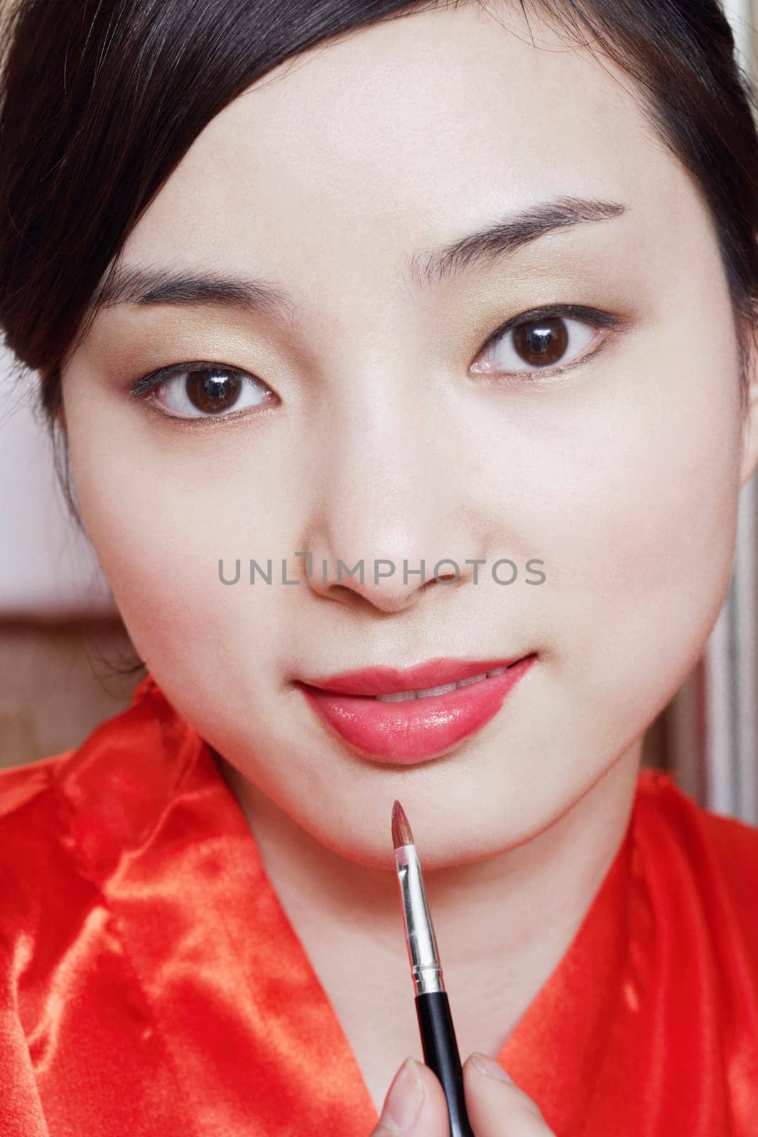 Portrait of a young woman applying lip gloss