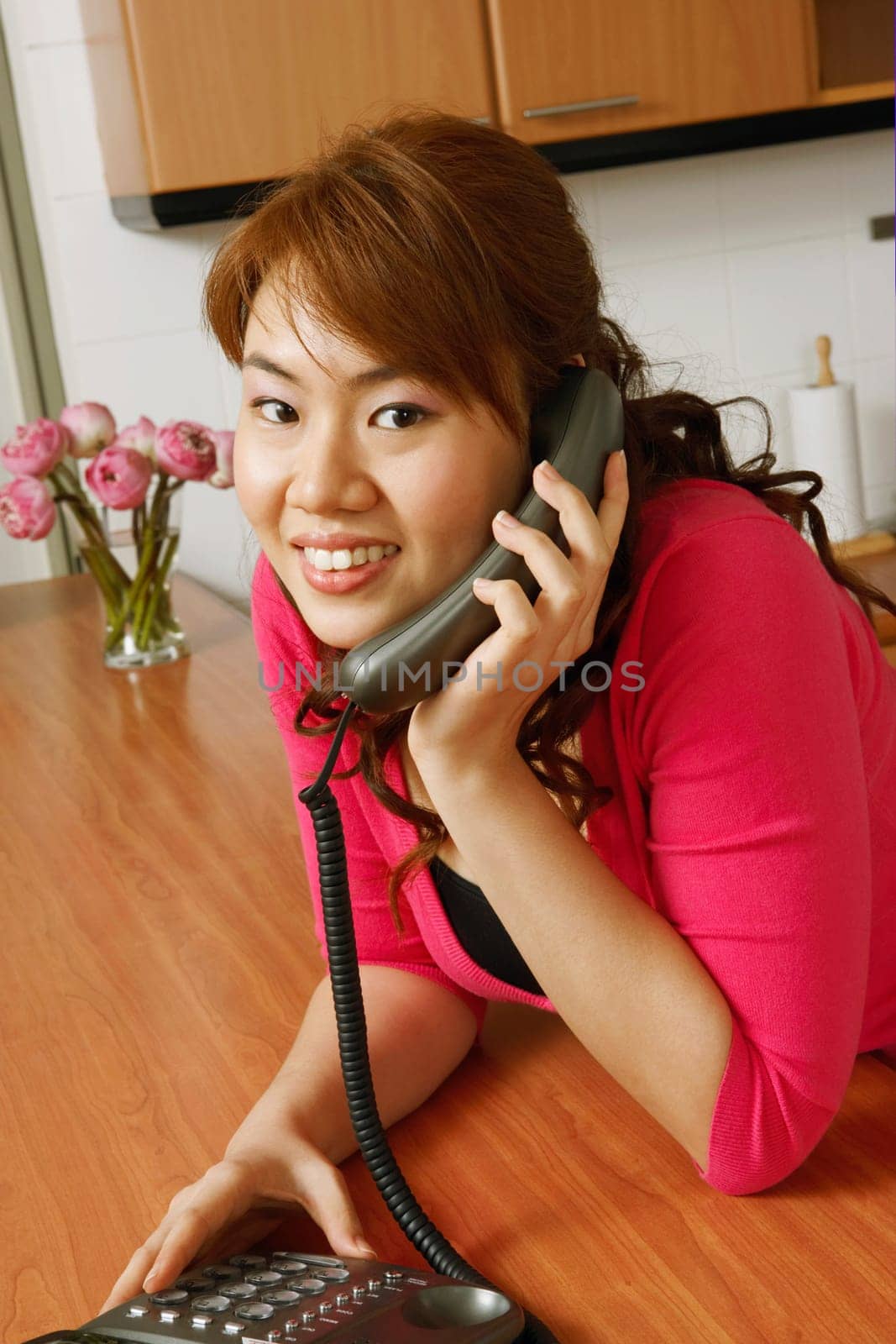 Portrait of a young woman using a telephone in the kitchen