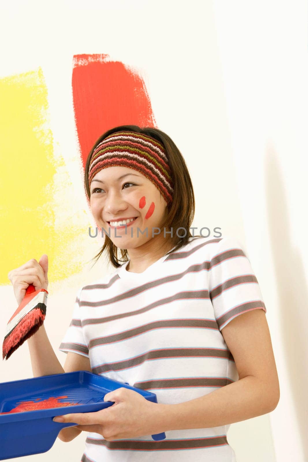 Close-up of a young woman holding a paint tray and a paintbrush