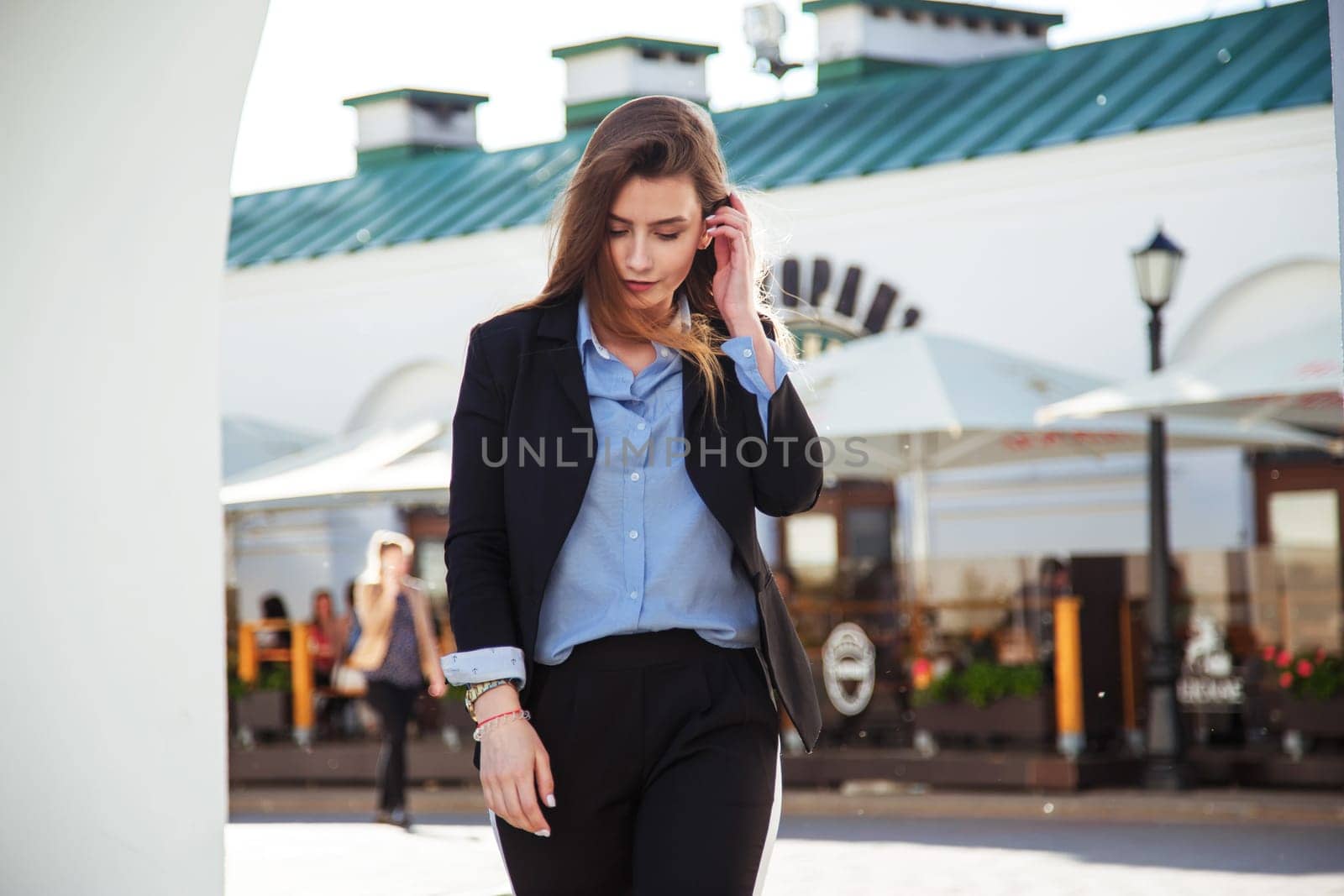 Young brunette woman in formal suit walking old town. Girl weared in blue shirt and black jacket.
