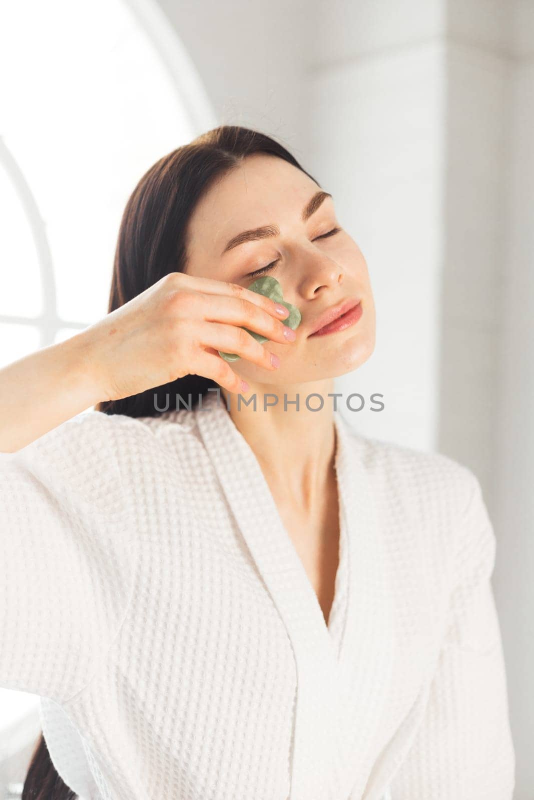 Young woman doing face Gua sha - chinese traditional massage