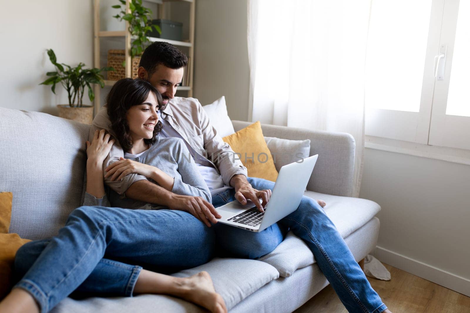 Happy couple using laptop relaxing sitting on the sofa. Copy space. Lifestyle and technology.